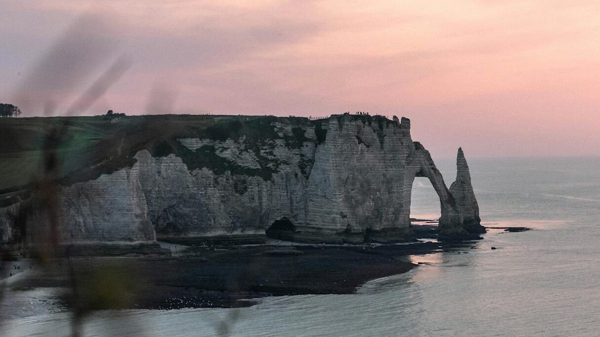 Breathtaking view of Étretat cliffs at sunset in Normandy, France, showcasing the natural beauty of the seascape.