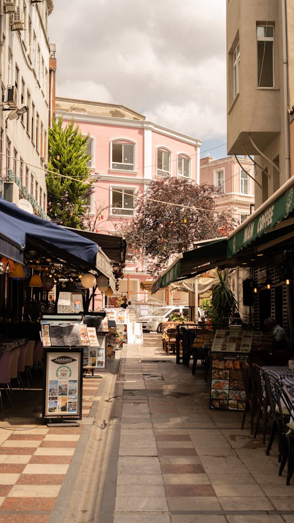 Beautiful alley in İstanbul with cafes and pink building, perfect for travel imagery.