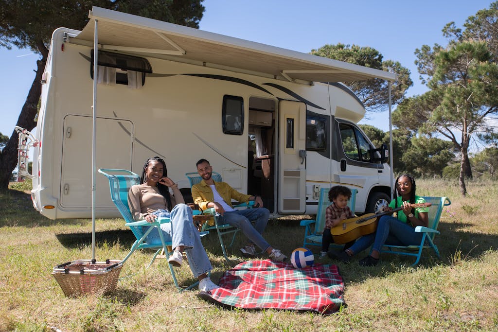 Smiling family enjoying a camping trip in Portugal with their campervan, relaxing with leisure activities.
