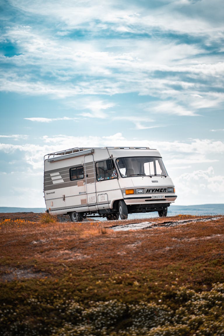Motorhome on a scenic landscape in Vardø, Norway, under a blue sky.