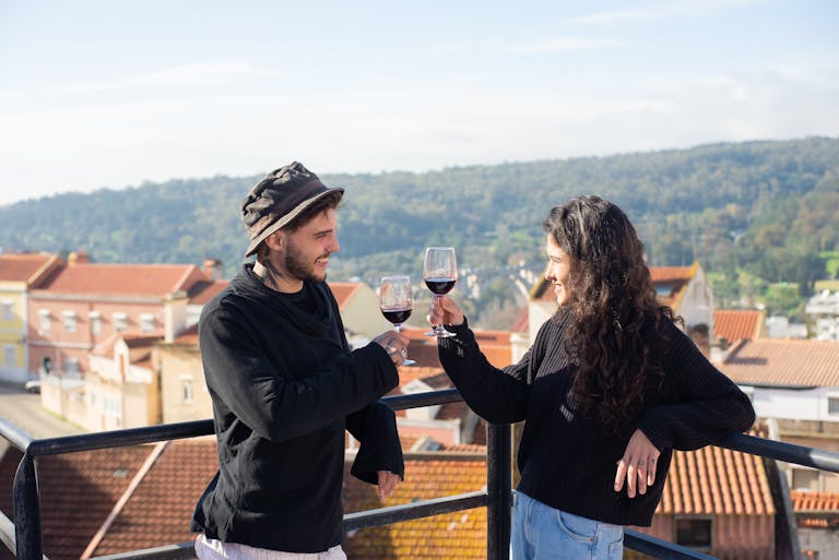 Two friends enjoying wine and celebrating on a picturesque rooftop in Portugal.