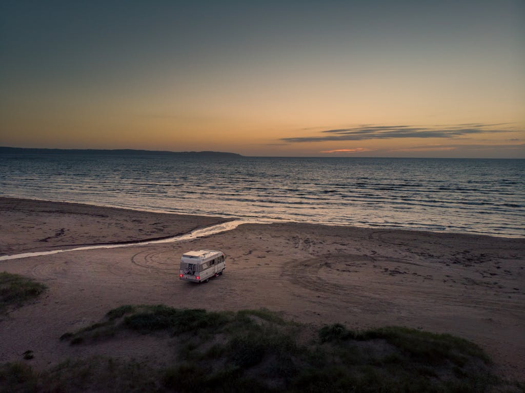 Camper van parked on the sandy beach of Hallands län, Sweden at sunset with ocean view.